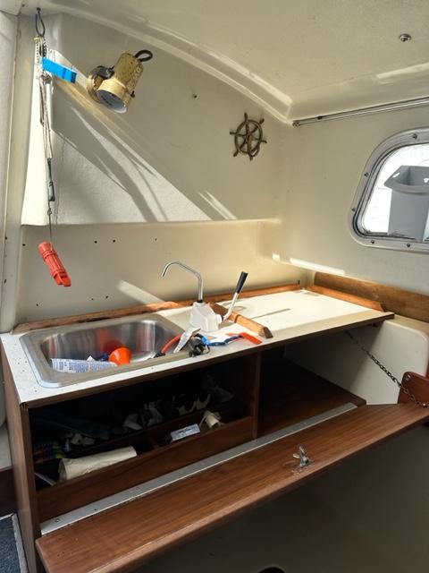 Slide: The Image of 1978 Pearson 26 sailboat interior with sink, storage, and nautical decor. - 21