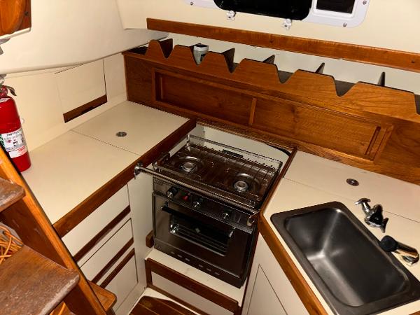 Slide: The Image of Compact galley kitchen in 1989 Pearson 31 sailboat with stove, sink, and wooden cabinetry. - 23