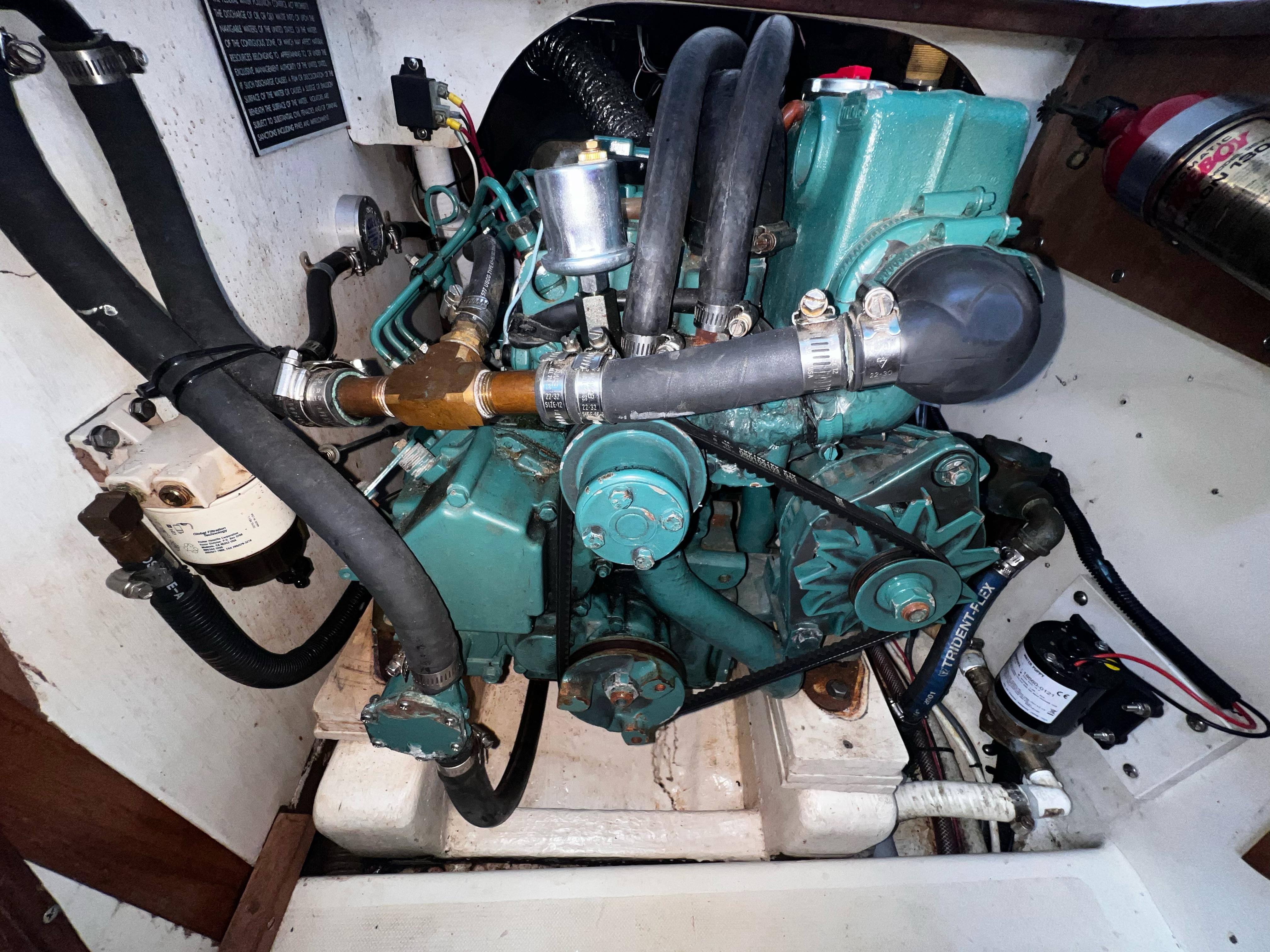 Slide: The Image of Engine compartment of a 1980 Pearson 32 sailboat, featuring hoses and mechanical components. - 23