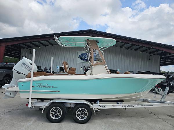 Slide: The Image of 2025 Pioneer 202 Islander boat on trailer, turquoise hull, under cloudy sky. - 1