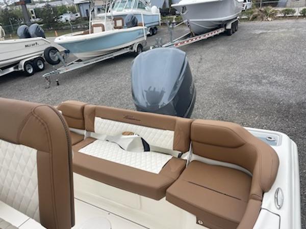 Slide: The Image of 2024 Pioneer 222 Islander boat with tan and white seating, docked near other boats. - 4