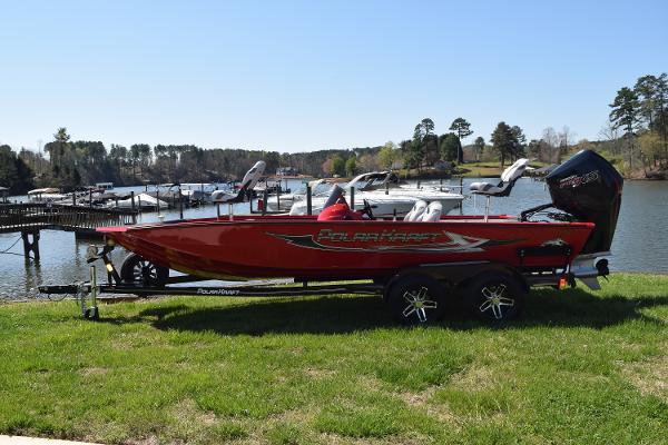 Slide: The Image of 2022 Polar Kraft Bass TX 195 Pro boat on trailer by a scenic lake. - 0