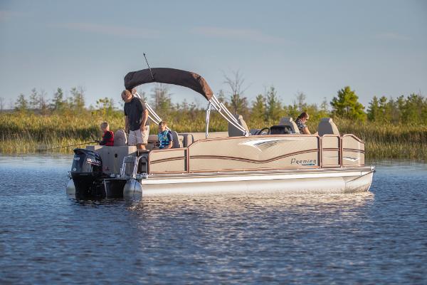 Slide: The Image of 2023 Premier 220 Castaway pontoon boat on a serene lake. - 0