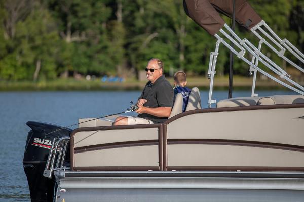 Slide: The Image of Man fishing on a 2023 Premier 220 Castaway pontoon boat in a serene lake. - 2