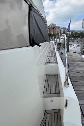 Slide: The Image of Prestige 63 yacht, 2017 model, docked with wooden steps and railing, cityscape in background. - 10