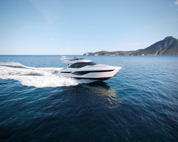 Slide: The Image of 2025 Princess 50 Flybridge yacht cruising on open sea with scenic island backdrop. - 0