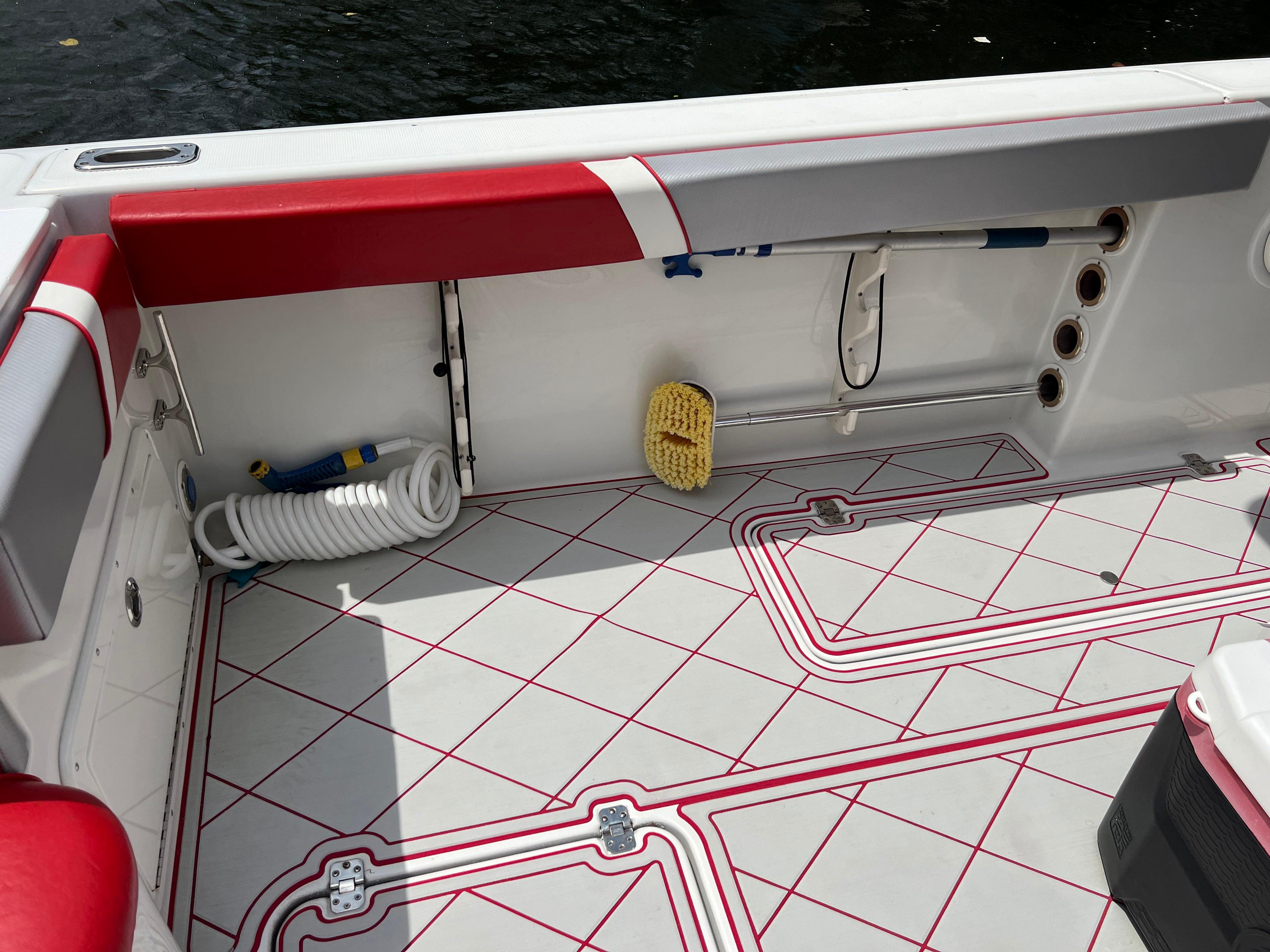 Slide: The Image of 2016 Pro-Line 3400 Cuddy boat deck with red and white detailing, hose, and cleaning brush. - 10