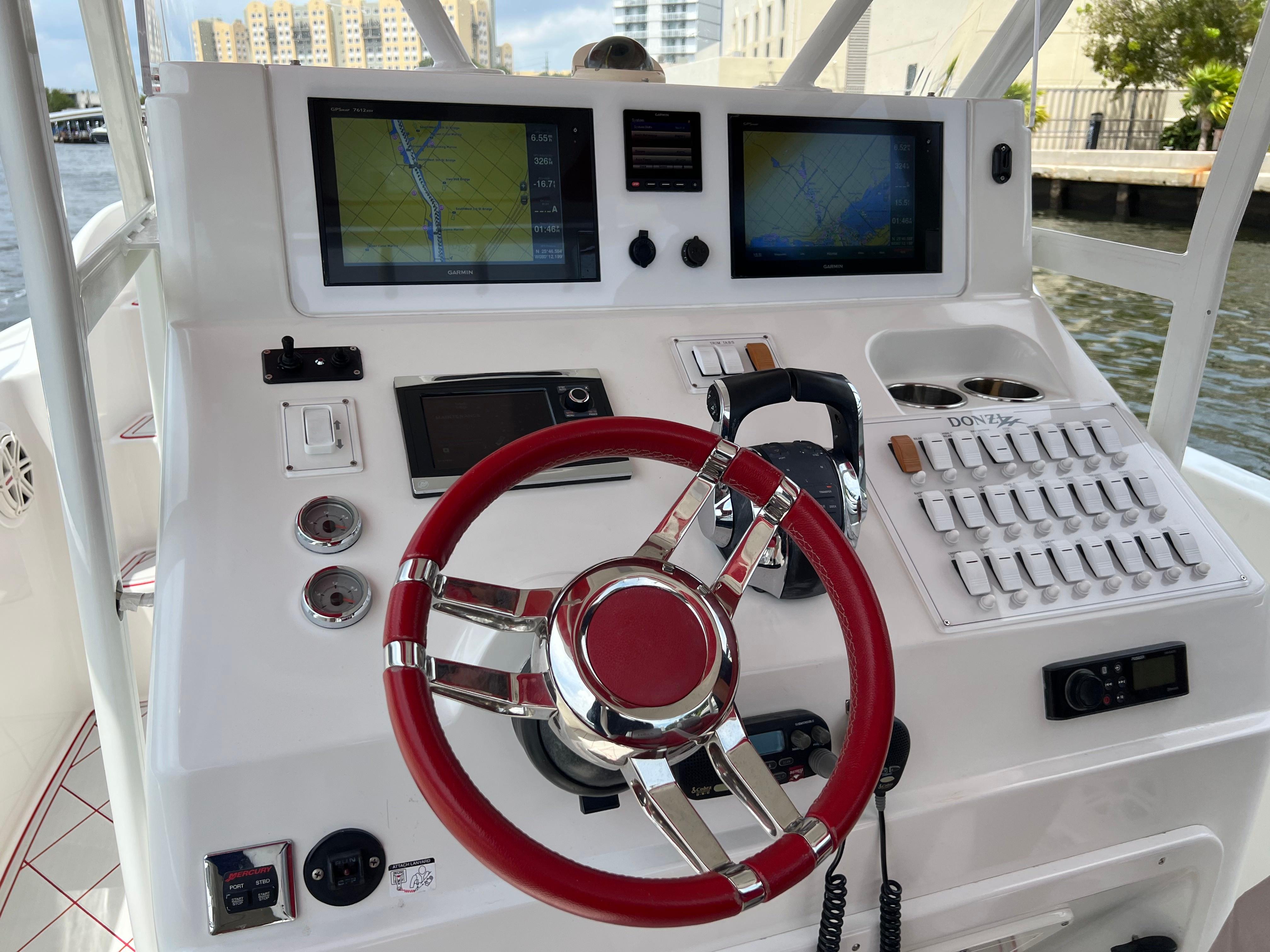 Slide: The Image of Pro-Line 3400 Cuddy 2016 boat dashboard with red steering wheel, navigation screens, and control panel. - 19