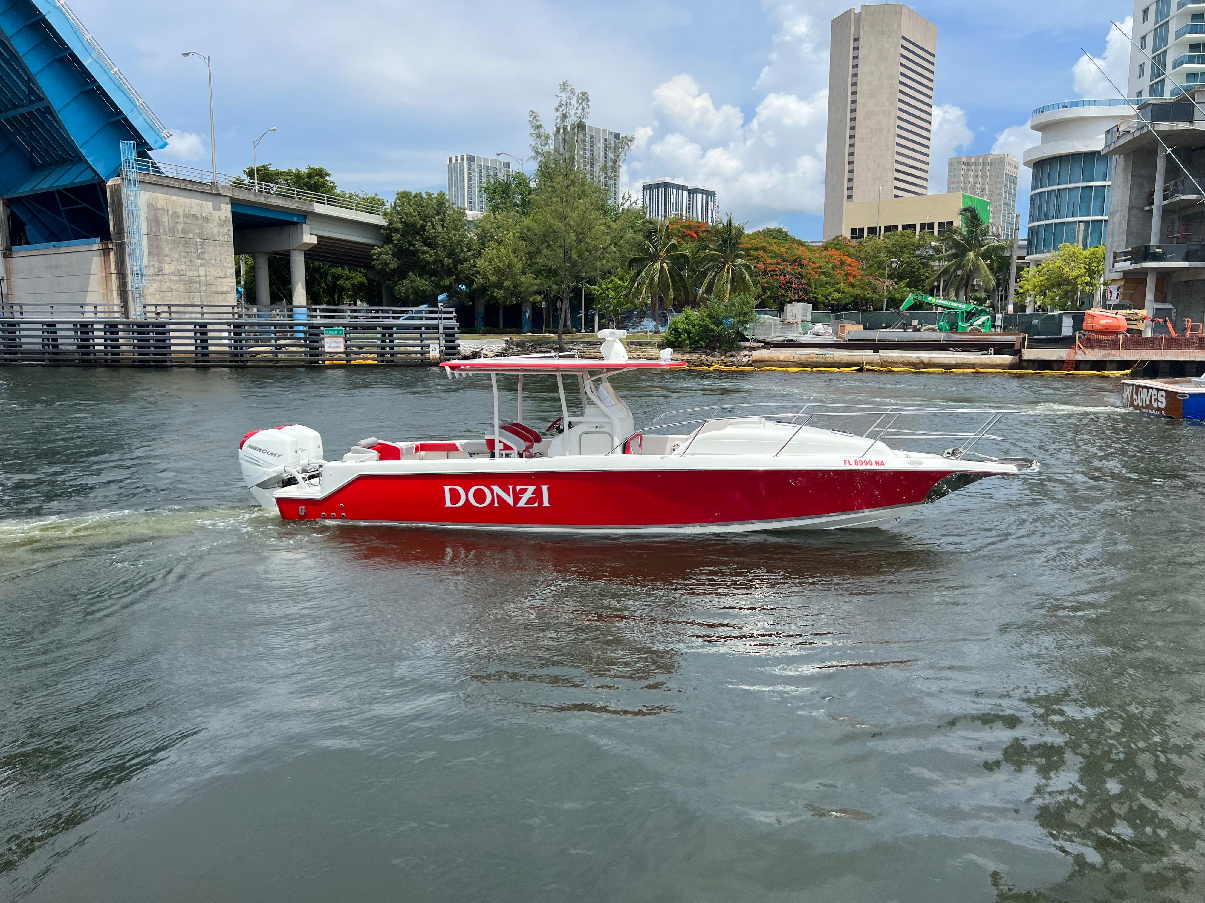 Slide: The Image of Red 2016 Pro-Line 3400 Cuddy boat named Donzi cruising near a city bridge. - 5