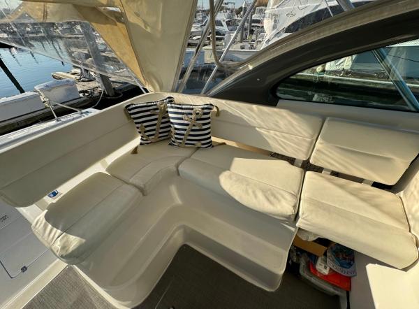 Slide: The Image of 2002 Pursuit 3800 Express boat interior with white seating and striped pillows. - 7