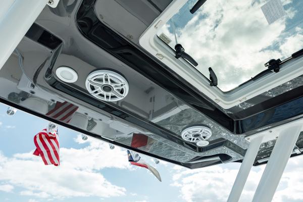 Slide: The Image of 2022 Pursuit S 328 boat roof with speakers and flags against a cloudy sky. - 36