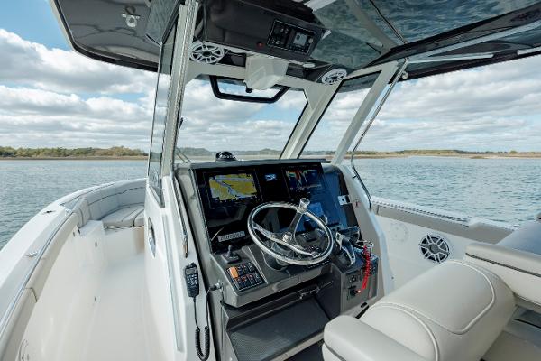 Slide: The Image of 2022 Pursuit S 328 boat cockpit with navigation system and steering wheel on open water. - 38