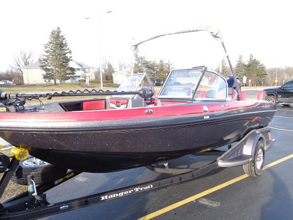 Slide: The Image of 2024 Ranger 1850 Reata boat on trailer, red and black exterior, parked outdoors. - 2