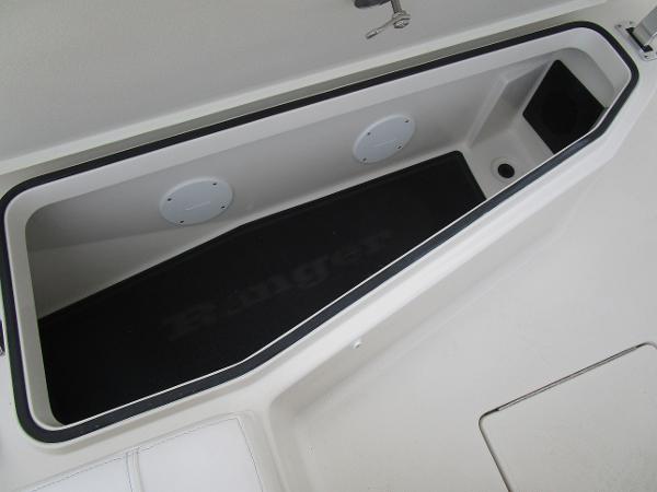 Slide: The Image of 2024 Ranger 2360 Bay boat storage compartment with black mat and drainage hole. - 29