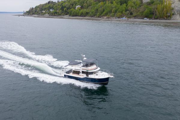 Slide: The Image of 2025 Ranger Tugs R-43 Command Bridge Luxury Edition cruising on a scenic coastal waterway. - 2