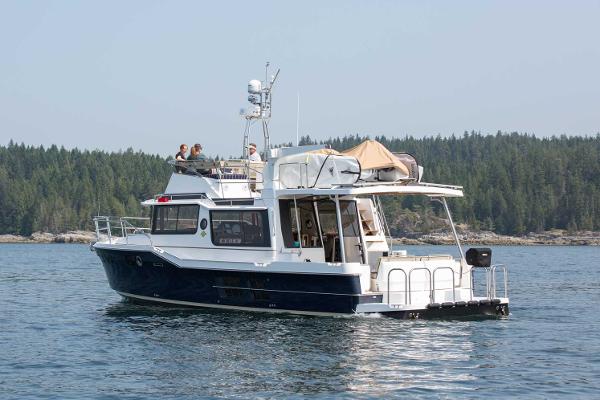 Slide: The Image of 2025 Ranger Tugs R-43 Command Bridge Luxury Edition on serene water, forested background. - 6