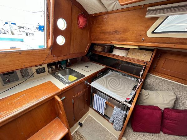 Slide: The Image of 1979 Ranger Yachts 30 interior with wooden cabinetry, sink, and cozy seating area. - 19