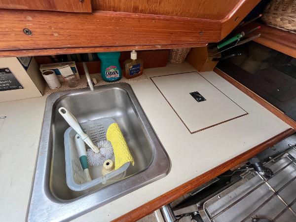 Slide: The Image of 1979 Ranger Yachts 30 galley sink area with cleaning supplies and countertop. - 23