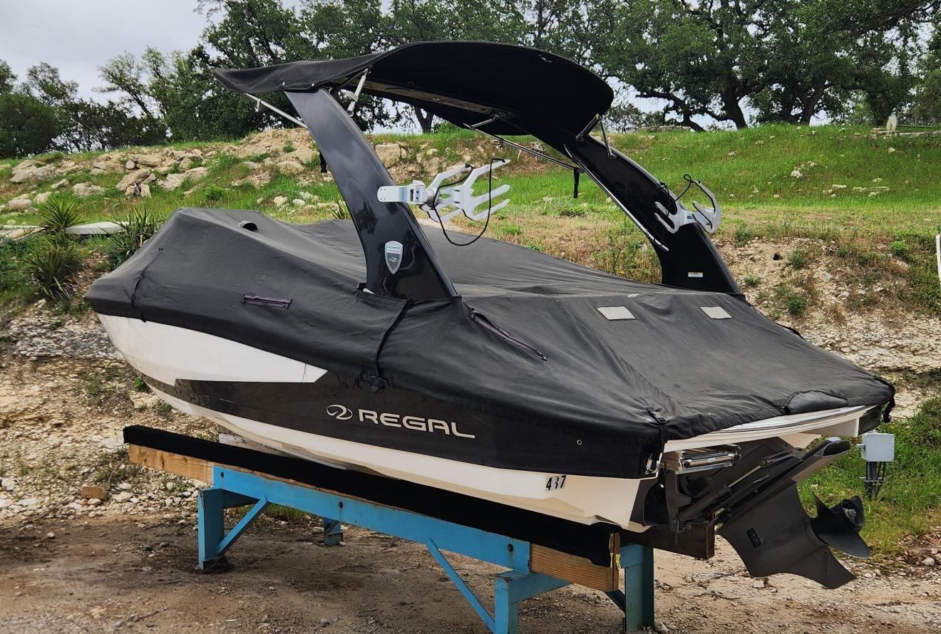 Slide: The Image of 2016 Regal 2100 Bowrider boat with black cover on a stand. - 1