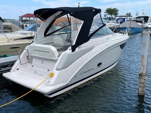 Slide: The Image of 2021 Regal 26 Express boat docked in marina, featuring sleek design and black canopy. - 0