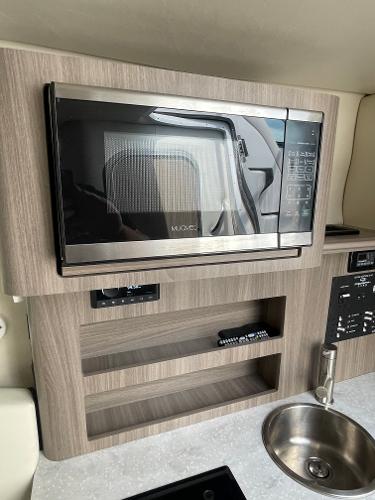 Slide: The Image of 2021 Regal 26 Express interior with microwave, shelving, and sink in compact kitchen area. - 17