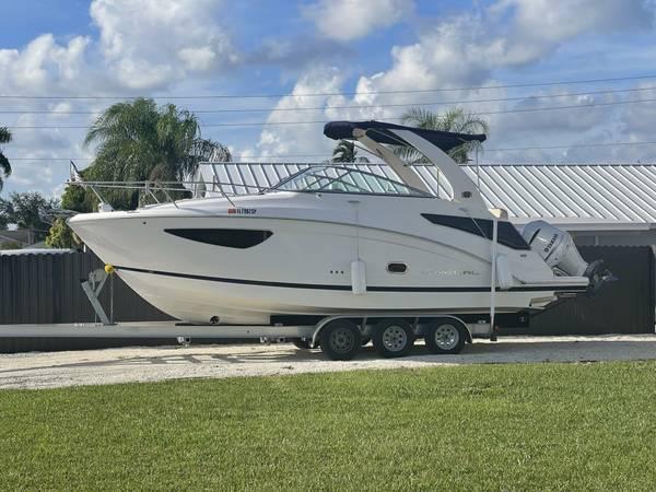 Slide: The Image of 2020 Regal 26 XO boat on trailer, parked outdoors under a cloudy sky. - 0