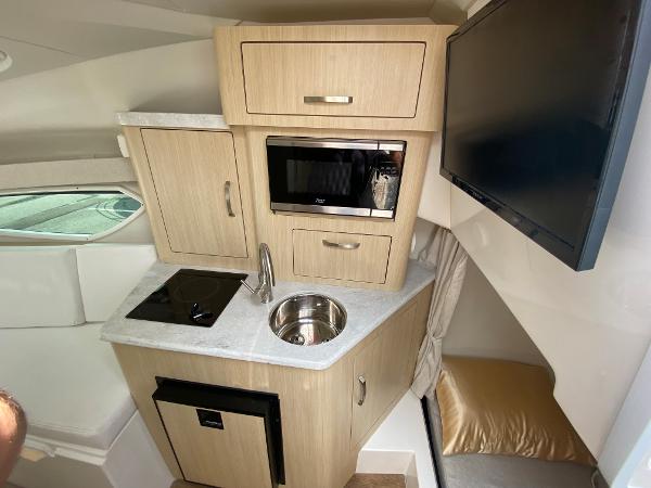 Slide: The Image of Compact kitchen area in 2025 Regal 28 Express boat with microwave, sink, and TV. - 28