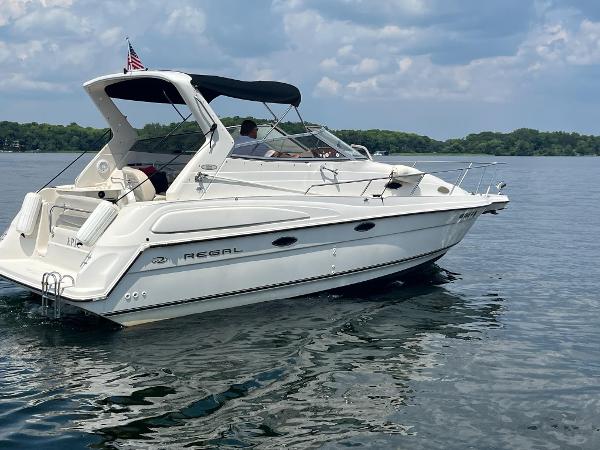 Slide: The Image of 1998 Regal 2760 boat cruising on a lake under a cloudy sky. - 1