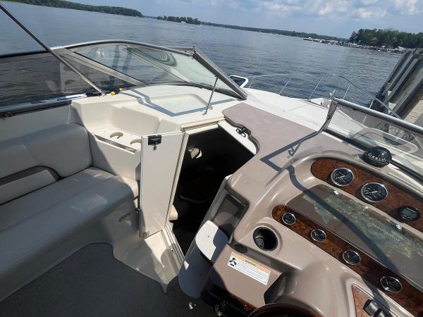 Slide: The Image of 1998 Regal 2760 boat interior with dashboard and open cabin door on a lake. - 13