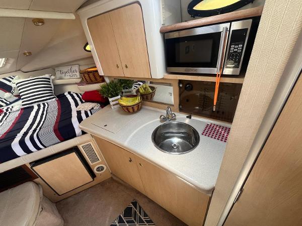 Slide: The Image of 1998 Regal 2760 boat interior with kitchenette, sink, microwave, and cozy sleeping area. - 18