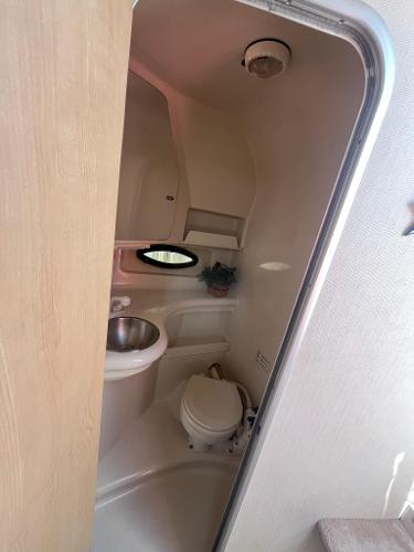 Slide: The Image of 1998 Regal 2760 boat bathroom with sink, toilet, and porthole window. - 19