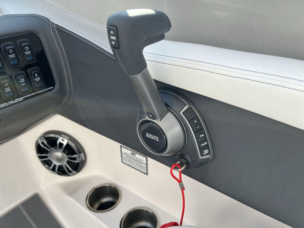 Slide: The Image of 2023 Regal LS6 Surf boat control panel with throttle, switches, and cup holders. - 18