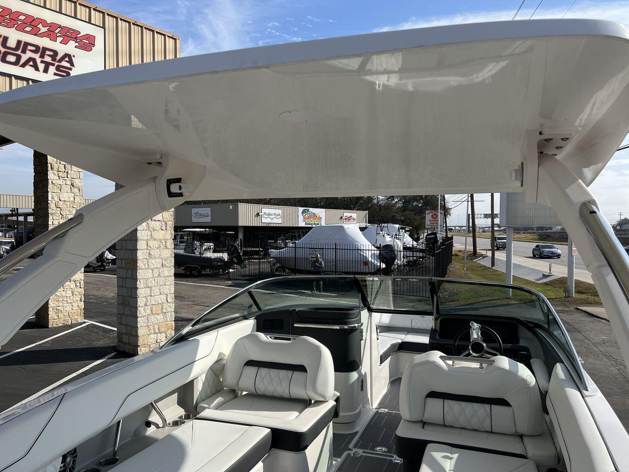 Slide: The Image of 2023 Regal LS6 Surf boat with white interior and canopy at a dealership. - 21