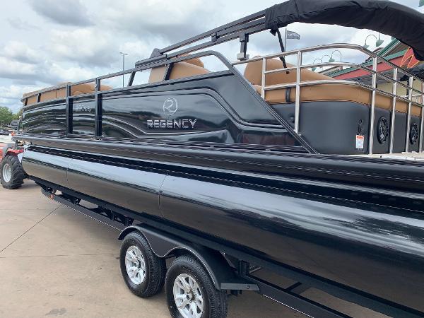 Slide: The Image of 2024 Regency 250 LE3 Sport pontoon boat on trailer, sleek black design. - 1