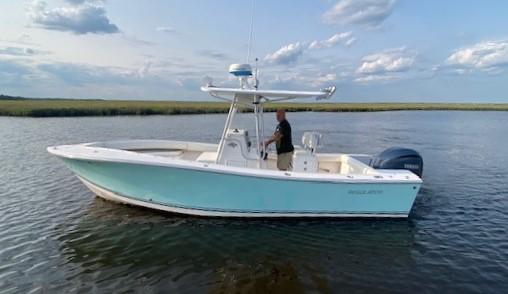 Slide: The Image of 2005 Regulator 23 Center Console boat on calm water under a partly cloudy sky. - 1