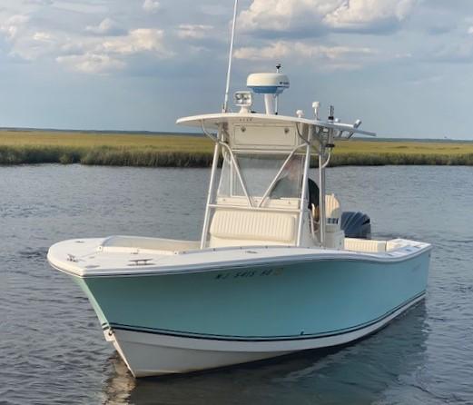 Slide: The Image of 2005 Regulator 23 Center Console boat on calm water under cloudy sky. - 2