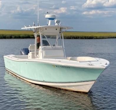 Slide: The Image of 2005 Regulator 23 Center Console boat on calm water under a cloudy sky. - 4