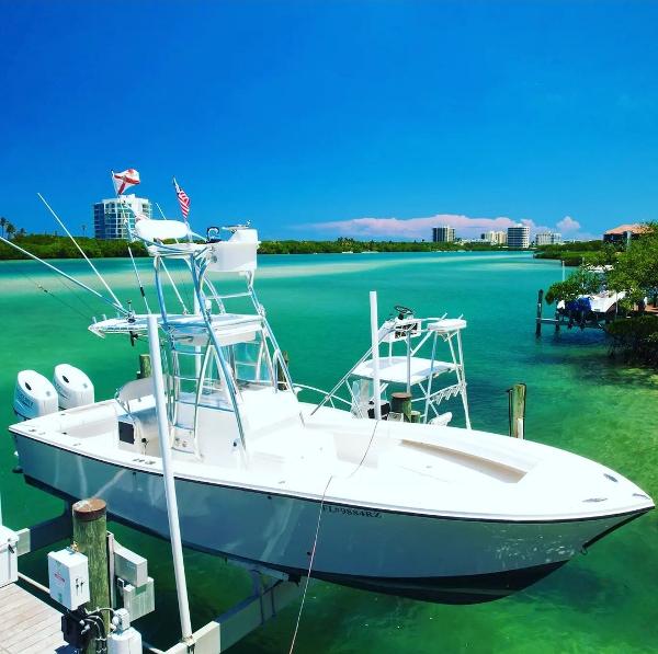 Slide: The Image of 2004 Regulator 26 Center Console boat docked in clear turquoise water on a sunny day. - 1