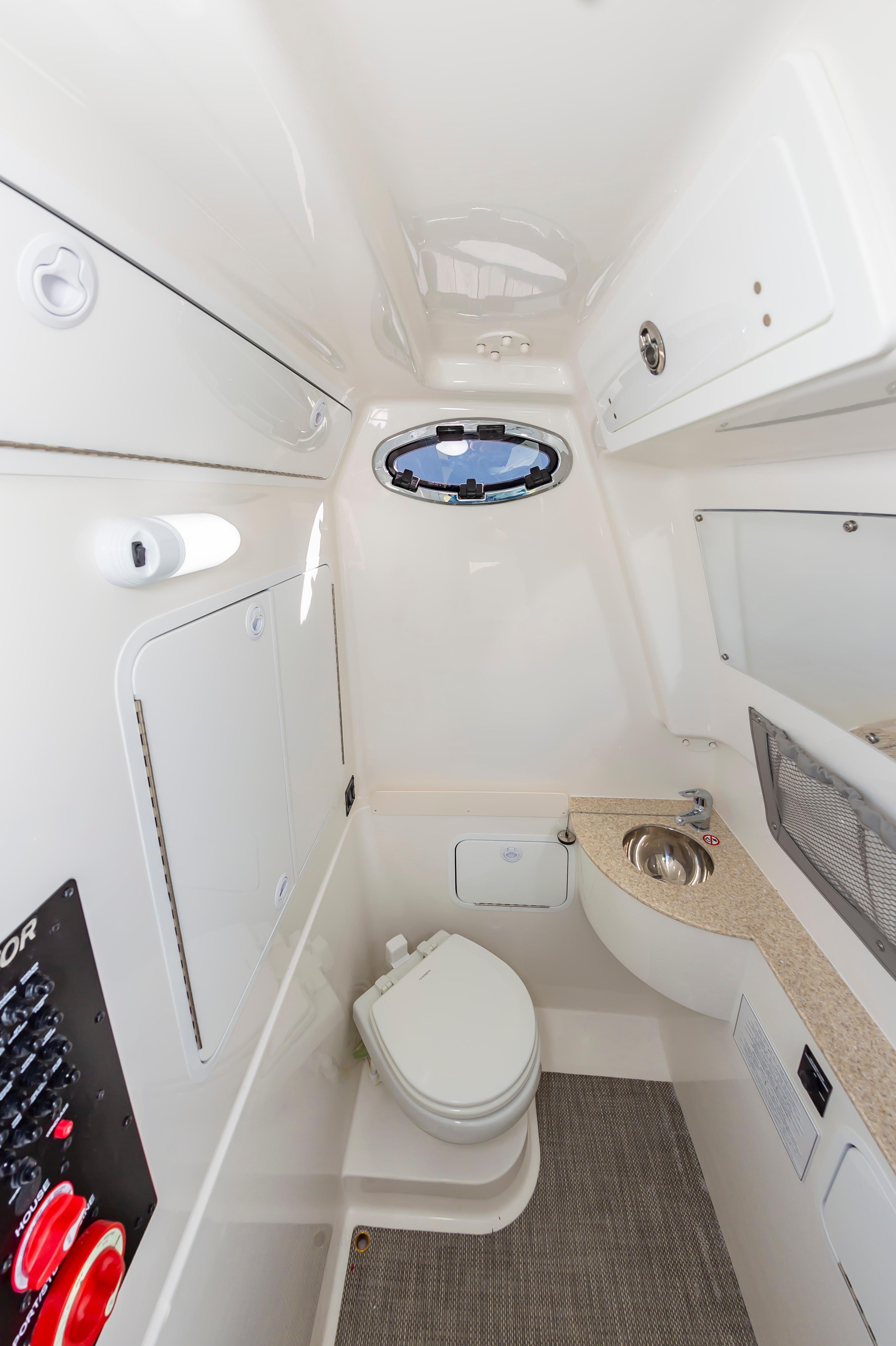 Slide: The Image of 2024 Regulator 28 boat interior bathroom with toilet, sink, and storage compartments. - 25