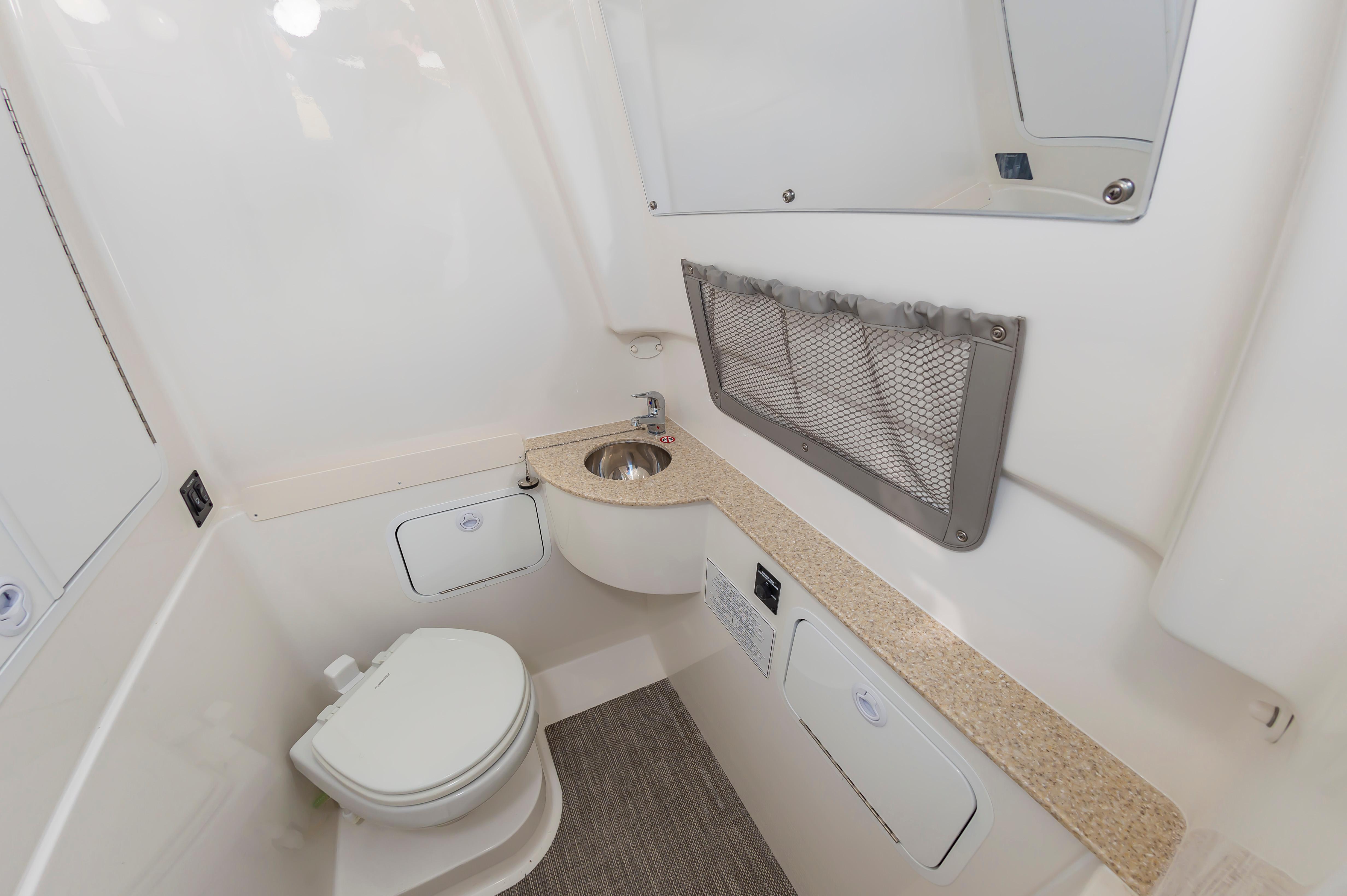 Slide: The Image of 2024 Regulator 28 boat bathroom with toilet, sink, and storage compartments. - 26