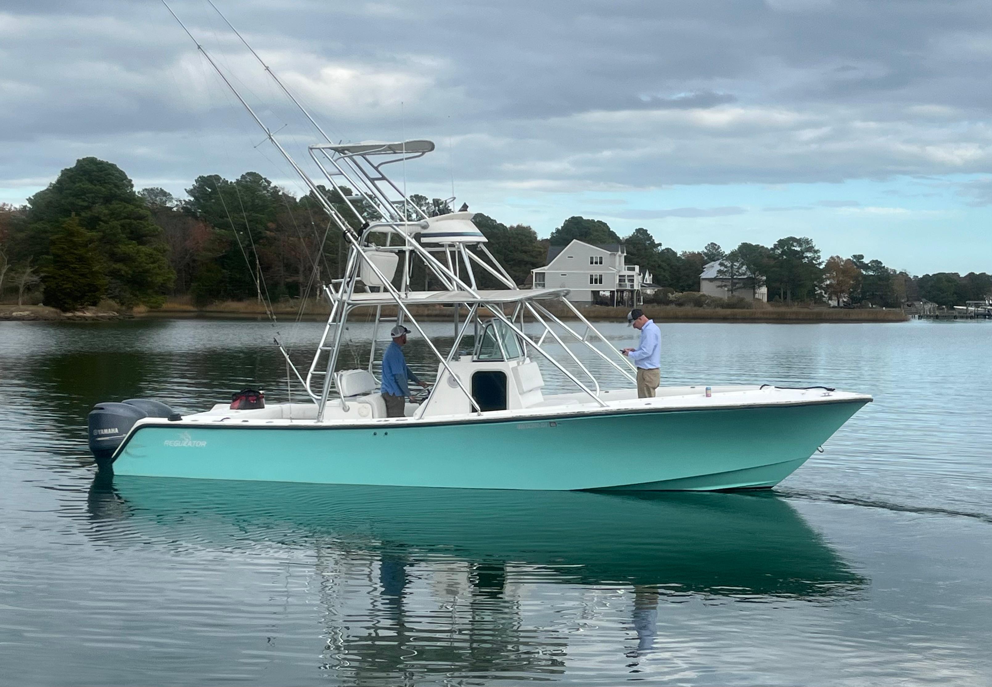 Slide: The Image of 2000 Regulator 32 Center Console boat on calm water with two people onboard. - 0