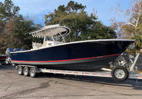 Slide: The Image of 2016 Regulator 34SS boat on trailer, dark blue hull, triple-axle, parked outdoors. - 10