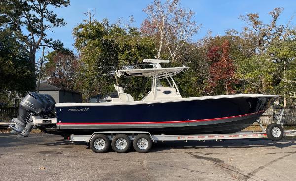 Slide: The Image of 2016 Regulator 34SS boat on trailer, parked outdoors with trees in background. - 13