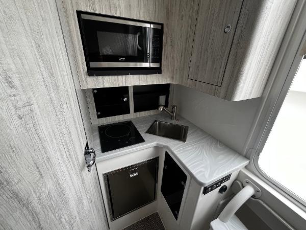Slide: The Image of 2024 Regulator 41 boat kitchen with microwave, stove, sink, and compact fridge. - 43