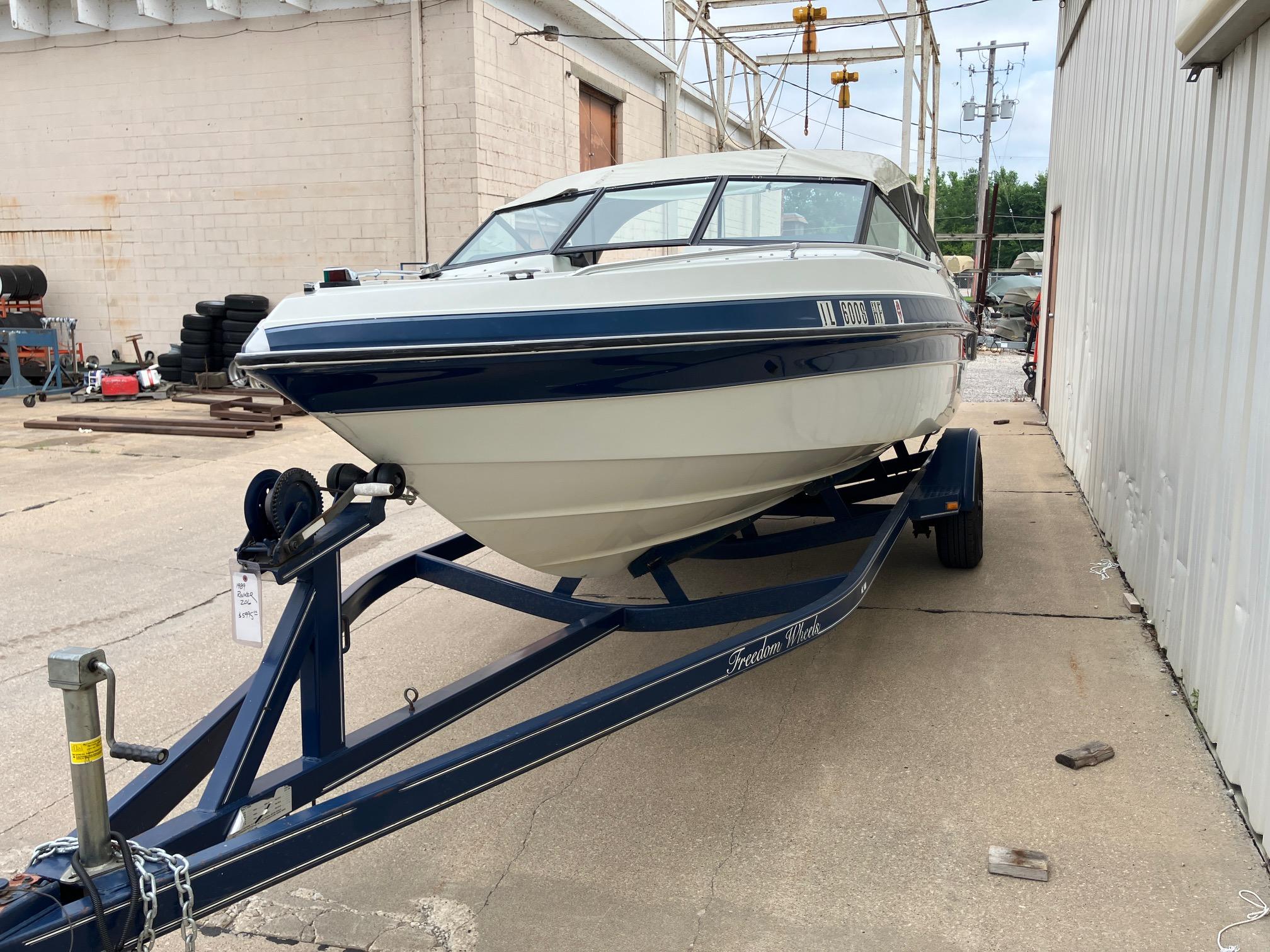Slide: The Image of 1989 Rinker 206 Open Bow boat on trailer, parked near industrial building. - 5
