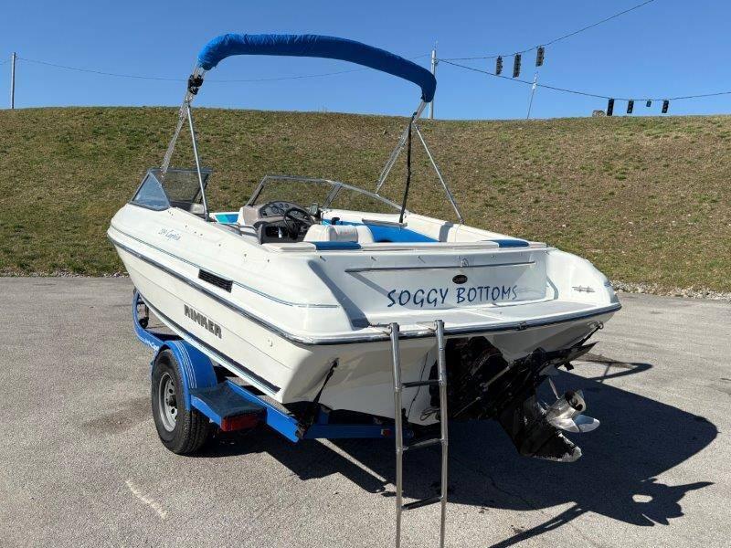 Slide: The Image of 1994 Rinker 209 Captiva boat on trailer, named "Soggy Bottoms," with blue canopy. - 11