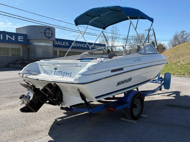 Slide: The Image of 1994 Rinker 209 Captiva boat on trailer with blue canopy, parked near a sales and service building. - 46