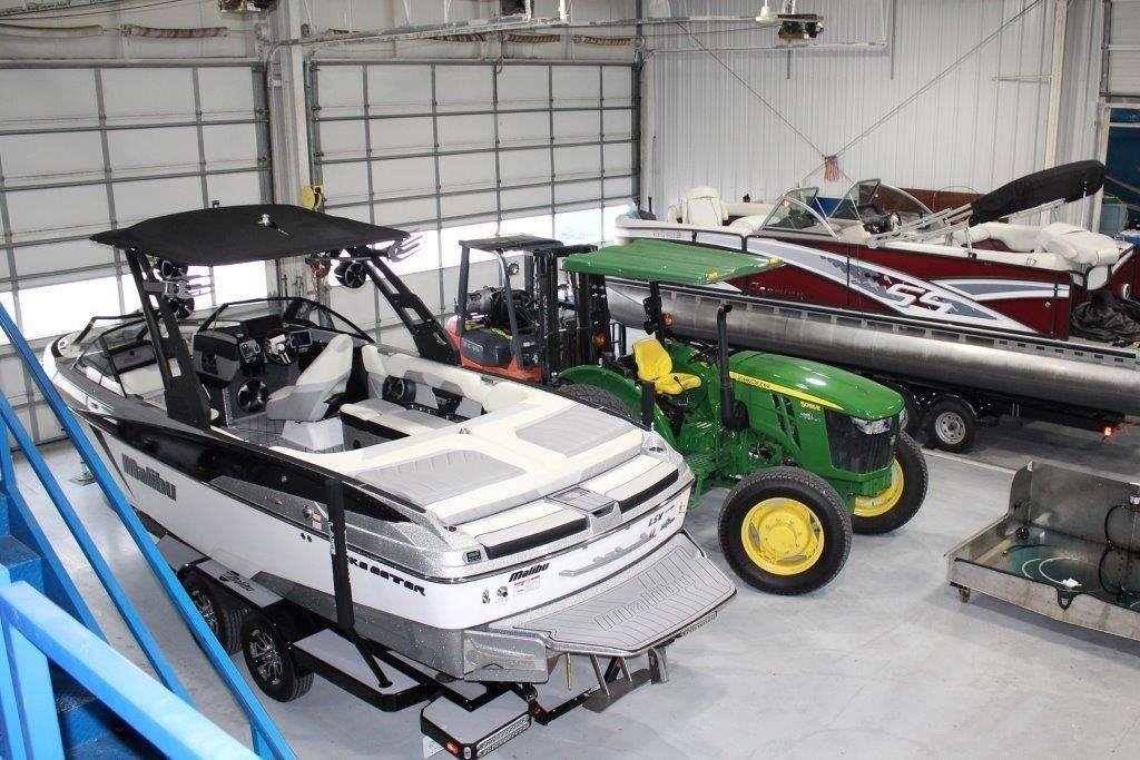 Slide: The Image of Indoor storage with boats and a tractor, featuring a 1994 Rinker 209 Captiva. - 9