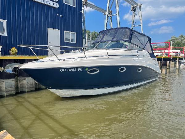 Slide: The Image of 2008 Rinker 260 Express Cruiser docked at marina, blue and white exterior. - 0