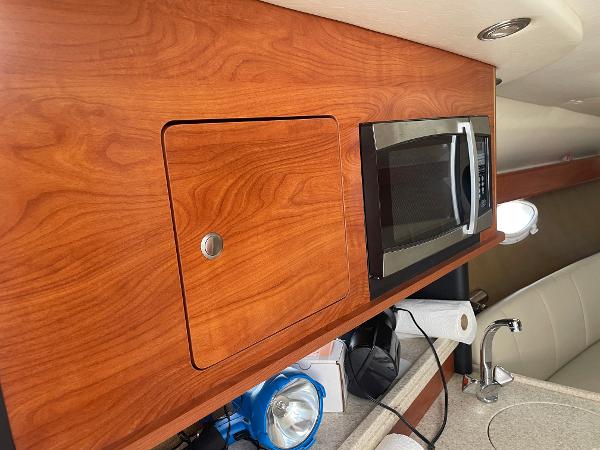 Slide: The Image of 2008 Rinker 260 Express Cruiser interior with wood cabinetry and microwave. - 14